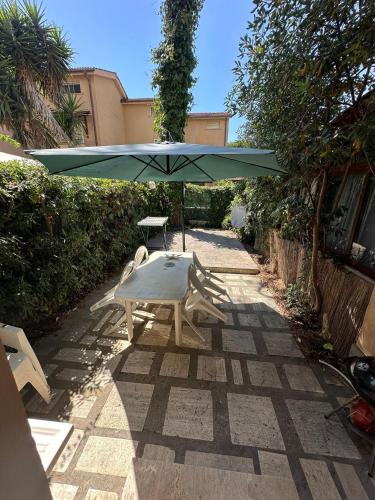 a table and a green umbrella on a patio at Un posto al sole in Fregene