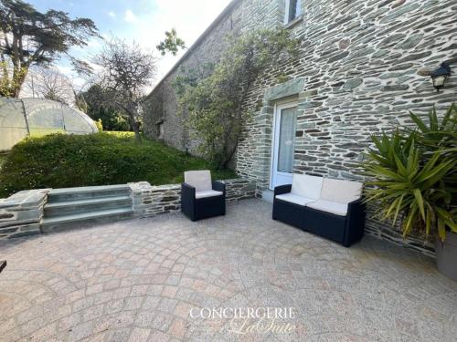 un patio avec deux chaises et un bâtiment dans l'établissement La croix Luce, à Cherbourg en Cotentin