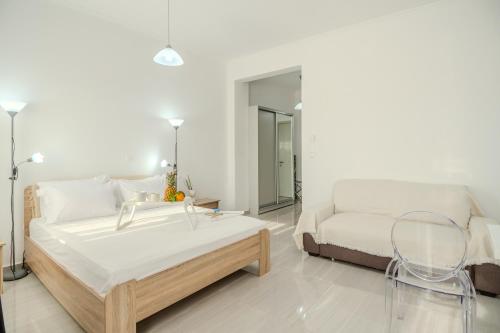 a white bedroom with a bed and a couch at Pezodromos Apartments in Filiatra