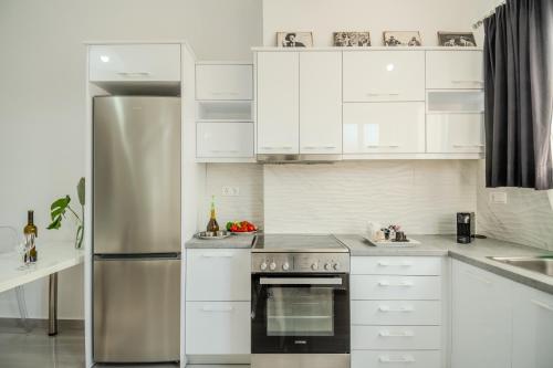 a kitchen with white cabinets and a stainless steel refrigerator at Pezodromos Apartments in Filiatra