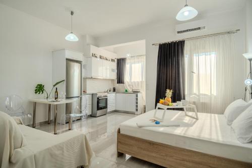 a white living room with a bed and a kitchen at Pezodromos Apartments in Filiatra