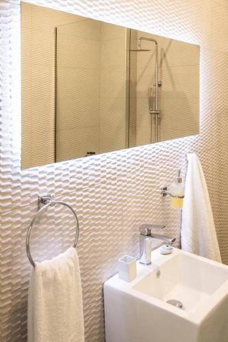 a white bathroom with a sink and a mirror at Pezodromos Apartments in Filiatra