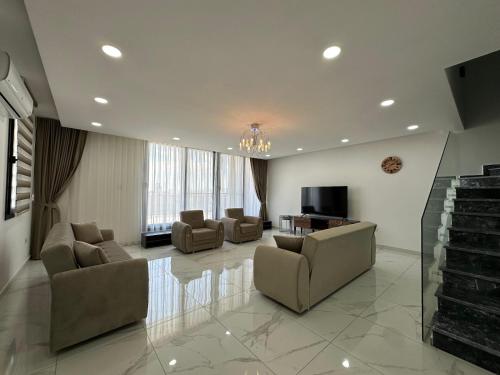 a large living room with couches and a television at ISKELE BAHCELER de KIRALIK TRIPLEX HAVUZLU LUKS VILLA in İskele