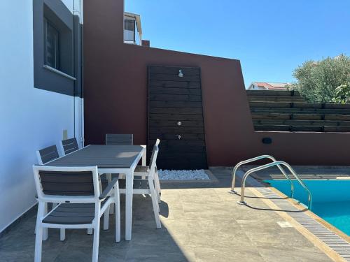 a patio with a table and chairs next to a swimming pool at ISKELE BAHCELER de KIRALIK TRIPLEX HAVUZLU LUKS VILLA in İskele