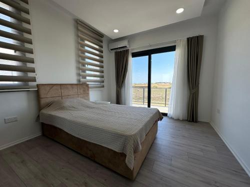 a bedroom with a bed and a large window at ISKELE BAHCELER de KIRALIK TRIPLEX HAVUZLU LUKS VILLA in İskele