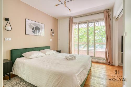 une chambre avec un grand lit et une grande fenêtre dans l'établissement Le Verdoyant - À Auteuil - 312B, à Paris
