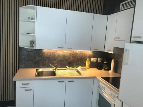 a kitchen with white cabinets and a sink at Girasole Orselina in Orselina
