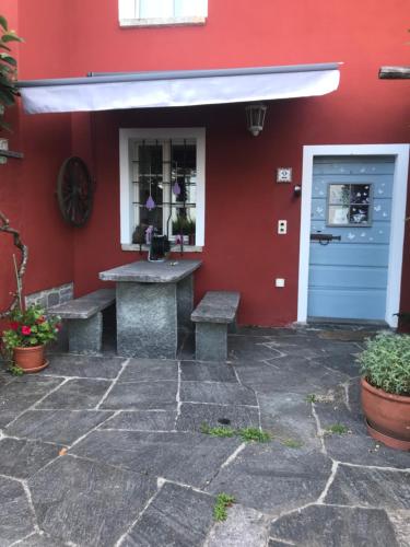a red building with benches and a blue door at Girasole Orselina in Orselina