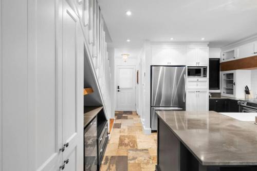 a kitchen with white cabinets and a stainless steel refrigerator at The Mountain View Condo in Mont-Tremblant