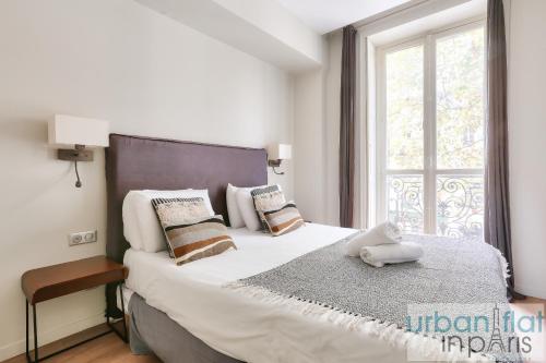 une chambre avec un grand lit avec une grande fenêtre dans l'établissement 60-LUXURY PARISIAN HOME SEBASTOPOL (2DG), à Paris