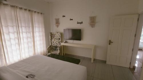 a bedroom with a bed and a tv on the wall at Trattorias Holiday Home in Varkala