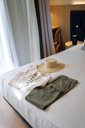 a hat sitting on top of a bed with a dress at Ocean Drive Sevilla in Seville