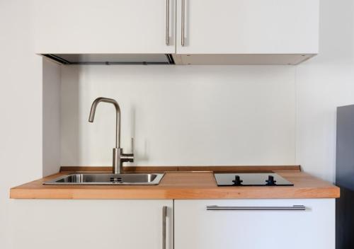a kitchen with a sink and white cabinets at Fully Furnished Pink Apartment 2 in Treviso