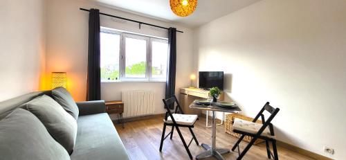 un salon avec un canapé et une table avec des chaises dans l'établissement Sauge Magnifique studio, RER B à 850m, Parking, à Bourg-la-Reine