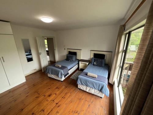 two beds in a room with wooden floors at Alfies House in Ponta Malongane