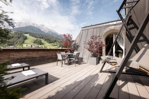 a wooden deck with a table and chairs on it at Post Hotel - Tradition & Lifestyle Adults Only in San Candido