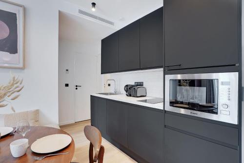 une cuisine avec des armoires noires et une table en bois dans l'établissement Luxurious apartment - 2BR-6P - Palais Opéra, à Paris