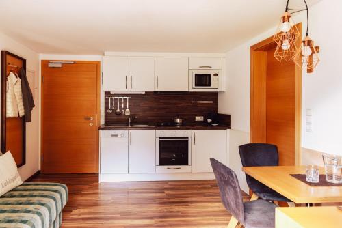 a kitchen with white cabinets and a table and a dining room at Ferienwohnen Mattle MIT IM RUCKSACK die SILVRETTA CARD PREMIUM in Kappl