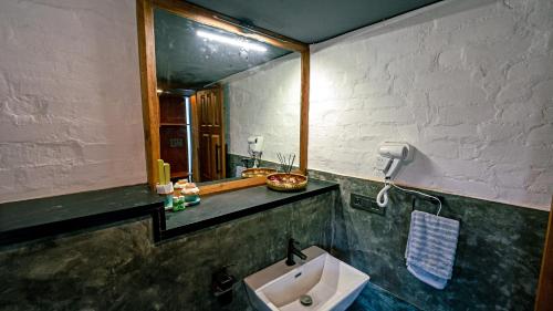 a bathroom with a sink and a mirror at Cove by Raho in Siddapur