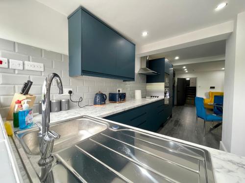 a kitchen with a stainless steel sink and blue cabinets at Luxury Guest House in Vibrant London Area in London