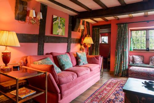 a living room with a pink couch and red walls at Llethrau Forest & Nature Retreats in Knighton