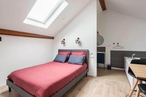 - une chambre avec un lit avec des draps rouges et une table dans l'établissement Grange Caliana, à La Vineuse