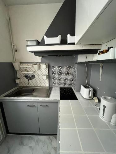 Il comprend une petite cuisine avec un évier et du carrelage. dans l'établissement Montmartre joli 2 pièces au pied du Sacré Coeur, à Paris