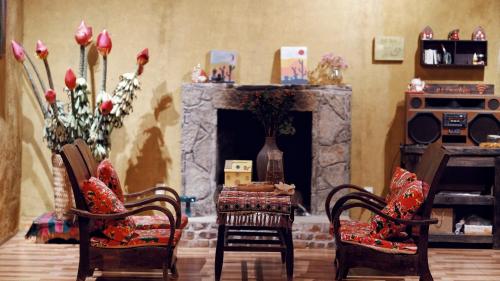 a living room with two chairs and a fireplace at Maison de Hill Home in Dồng Văn