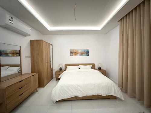 a bedroom with a large white bed and wooden cabinets at يملا Yamla in Al Madinah