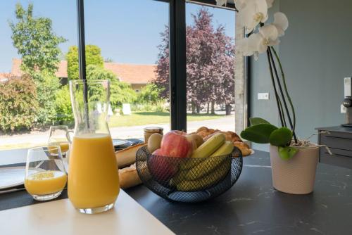 een tafel met een fruitschaal en een glas sinaasappelsap bij L'Artbanne Maison Hestia in Saint-Hilaire-le-Petit