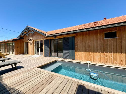 - une piscine sur une terrasse en bois à côté d'une maison dans l'établissement Villa Genêts - 3 suites parentales avec terrasse et piscine - Proche plage, à Gujan-Mestras