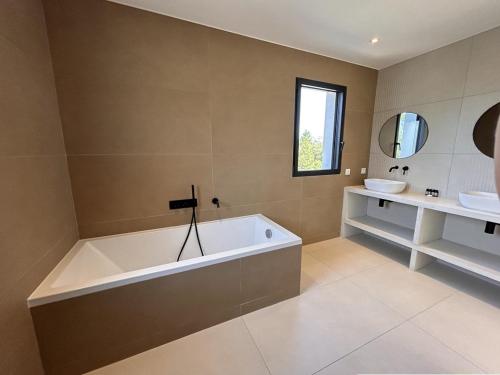 une grande salle de bain avec une baignoire et un lavabo dans l'établissement Bergerie Piana d'architecte neuve, 8 pers, piscine chauffée, à 10 min plage, à Gialla
