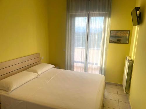 a bedroom with a white bed and a window at Appartamento Luigi in Alba Adriatica