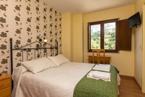a bedroom with a bed and a window at Hotel Rural Somiedo in Valle de Lago