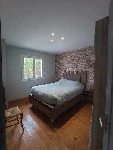 une chambre avec un lit et un mur de briques dans l'établissement Gîte entre lac, rivière et mer, à Le Pouget