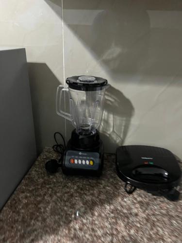 a blender sitting on the floor next to a black appliance at Kings place in Eldoret