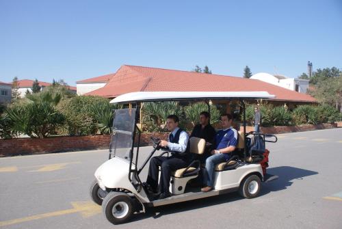 tres hombres montando un carro de golf calle abajo en The Crescent Beach Hotel, en Baku