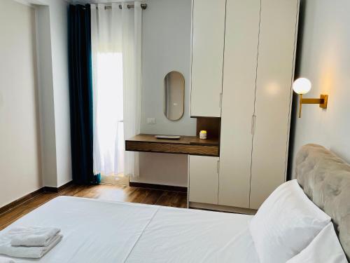 a bedroom with a bed and a vanity with a mirror at Adora City Center in Divjakë