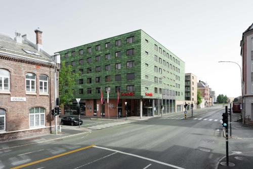an empty city street with a green building at Scandic Solsiden in Trondheim