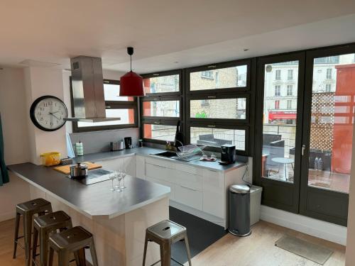 une cuisine avec un comptoir et une horloge au mur dans l'établissement Appartement Loft Terrasse - Saint Denis, à Saint-Denis
