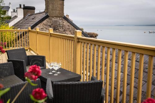a table with wine glasses and flowers on a balcony at Glan Y Don Moelfre in Moelfre