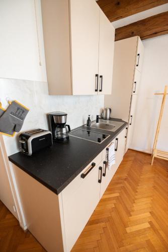 une cuisine avec des armoires blanches et un évier dans l'établissement Le Repaire du Chanceux, à Sélestat