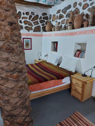 a bedroom with a bed and a stone wall at Tigmi Bulbul in Id AÃ¯ssa