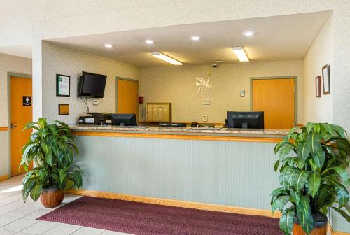 a hotel lobby with a reception counter with two plants at Quality Inn in Weston