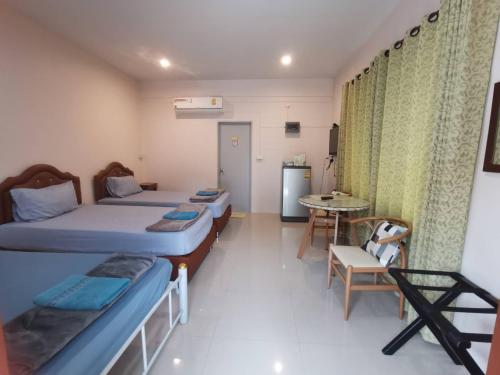 a room with two beds and a table and a table at Numhom Resort in Ban Nong Chum Saeng