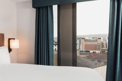a bedroom with a window with a view of a city at Staybridge Suites Newcastle by IHG in Newcastle upon Tyne