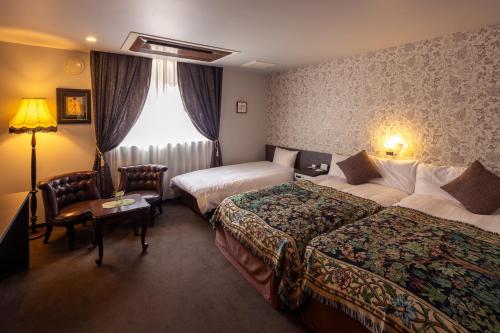 a hotel room with two beds and a window at Hotel Berlinetta Karuizawa in Karuizawa