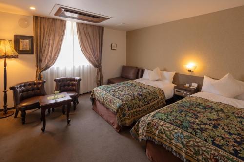 a hotel room with two beds and a couch at Hotel Berlinetta Karuizawa in Karuizawa