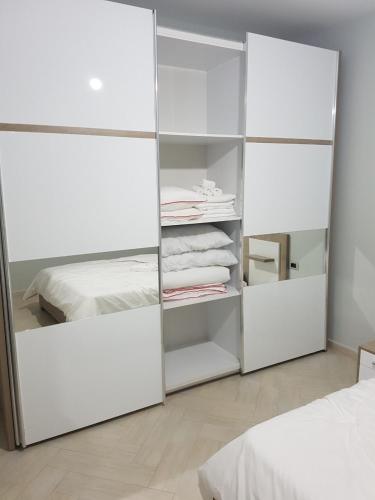 a white closet with white shelves and a bed at Blue Horizon Apartment in Sarandë