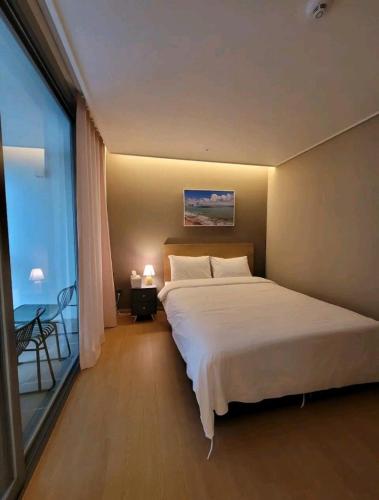 a bedroom with a large bed and a large window at Elbon the stay with A1 in Busan